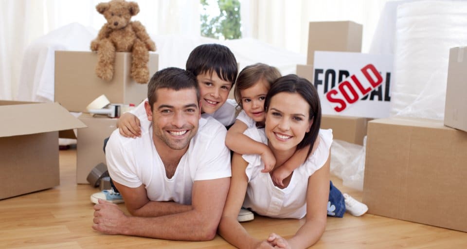 family of four in front of moving boxes