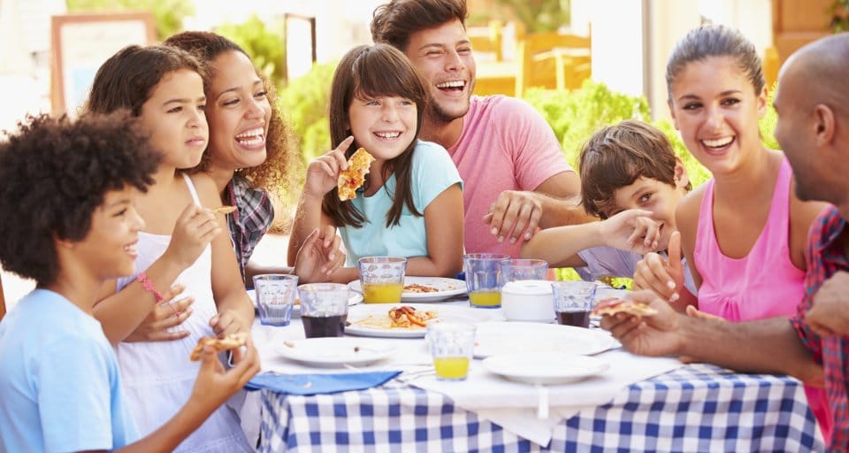 family smiling, eating around picnic table