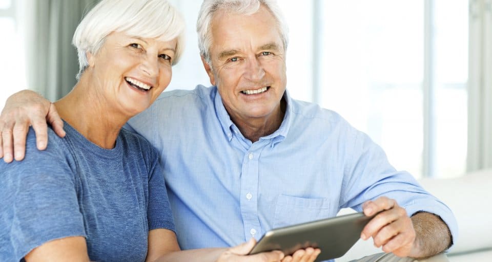 elderly couple smiling with laptop