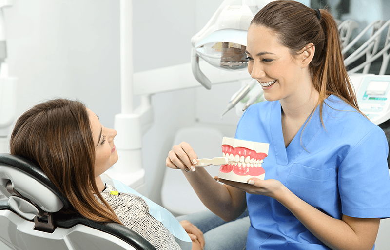 female dentist showing female patient tooth model